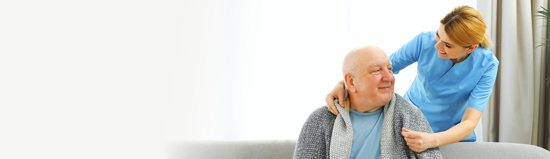 caregiver giving blanket to senior man