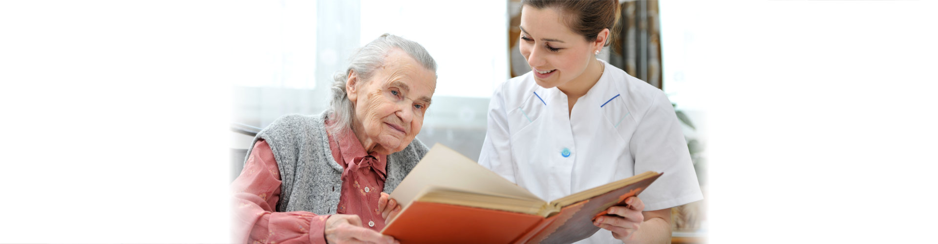 caregiver and elderly woman reading book