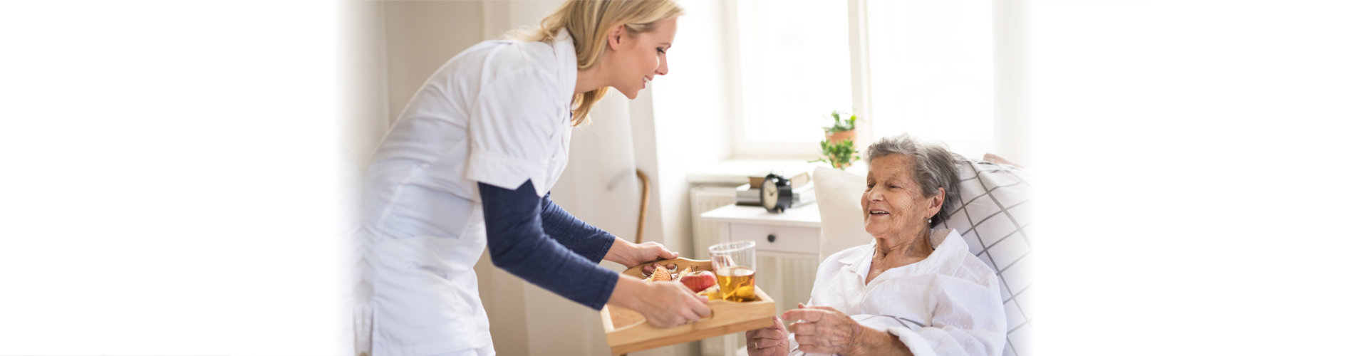 caregiver giving food to elderly woman