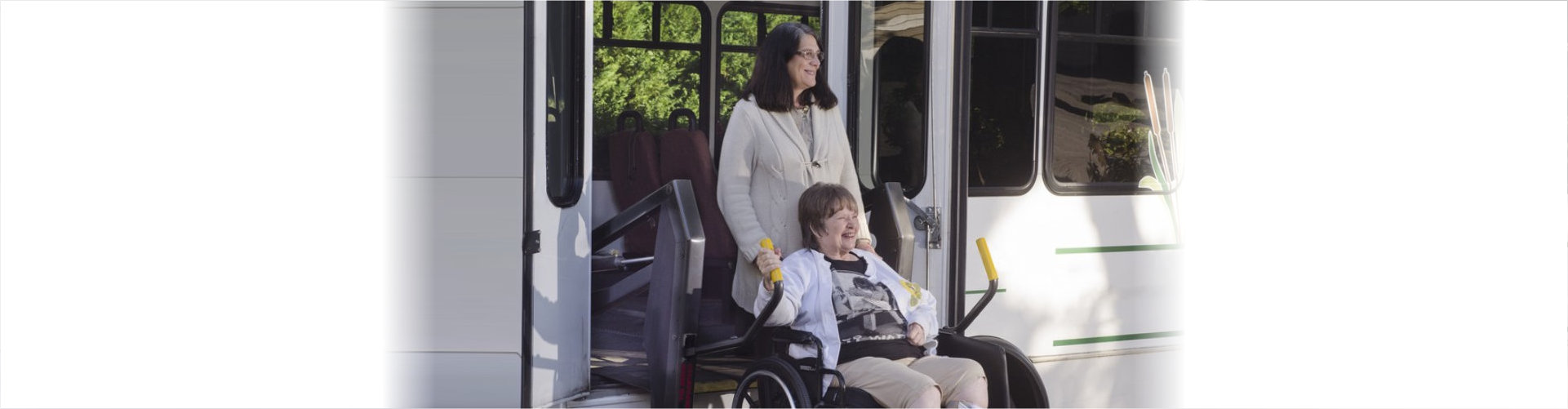 caregiver pushes wheelchair of elderly woman