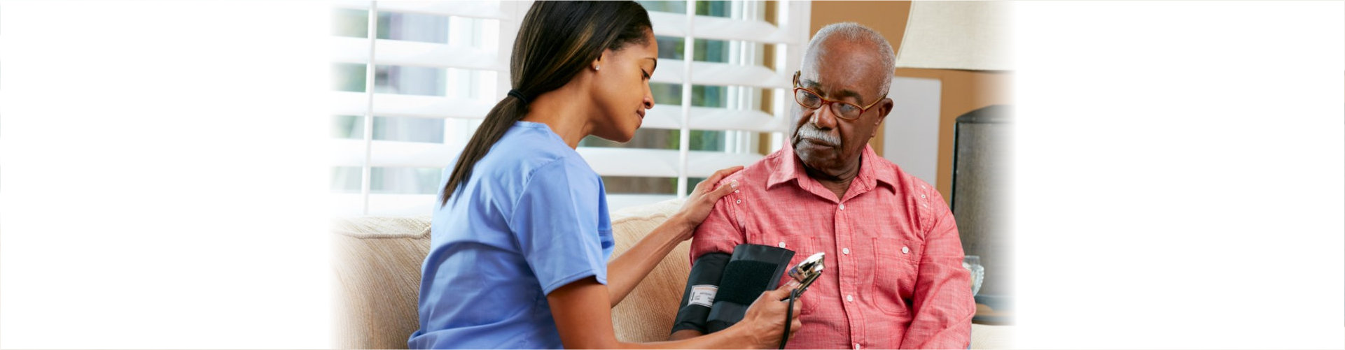 caregiver checking senior man's blood pressure