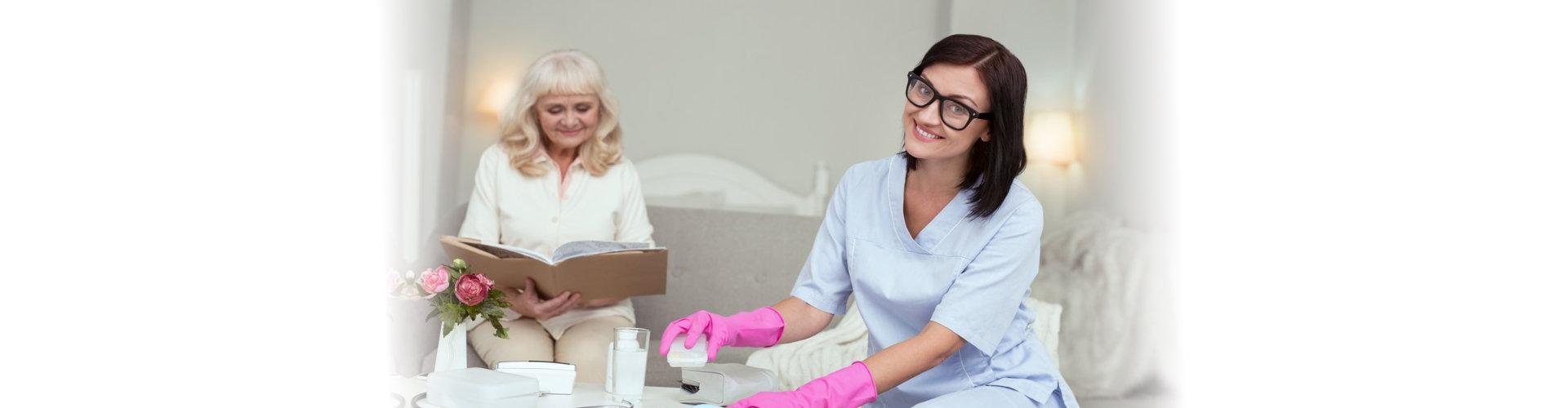 senior woman reading book while caregiver cleaning